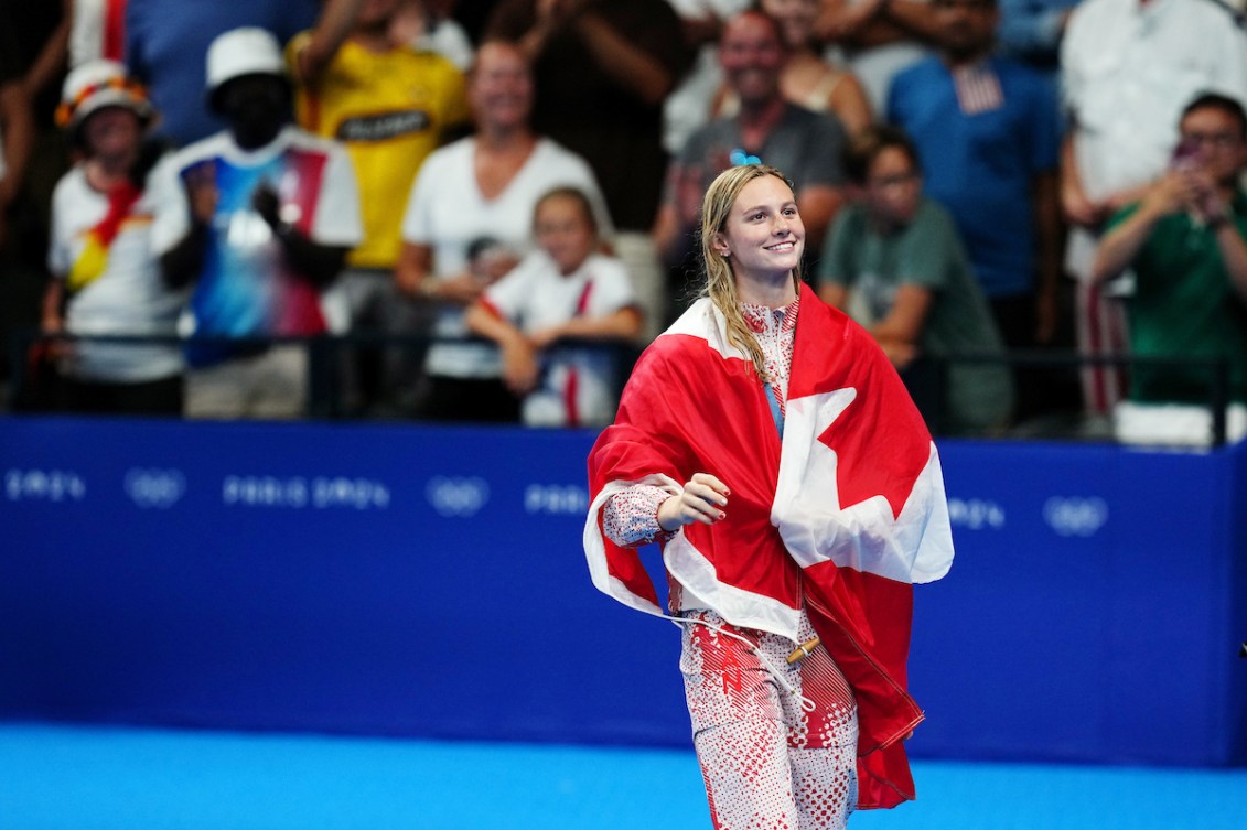 Summer McIntosh walks with a Canadian flag around her