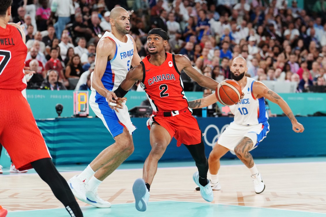 Shai Gilgeous-Alexander pushes past two French players with the ball