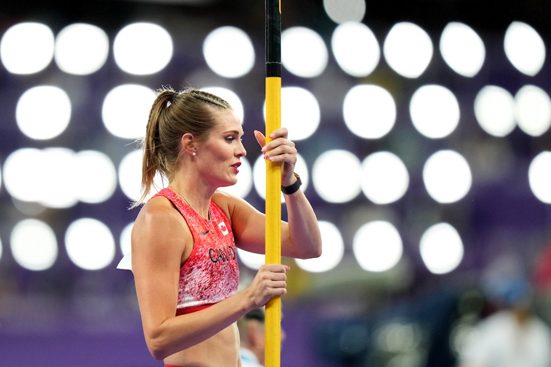 Alysha Newman stands while holding her yellow pole 