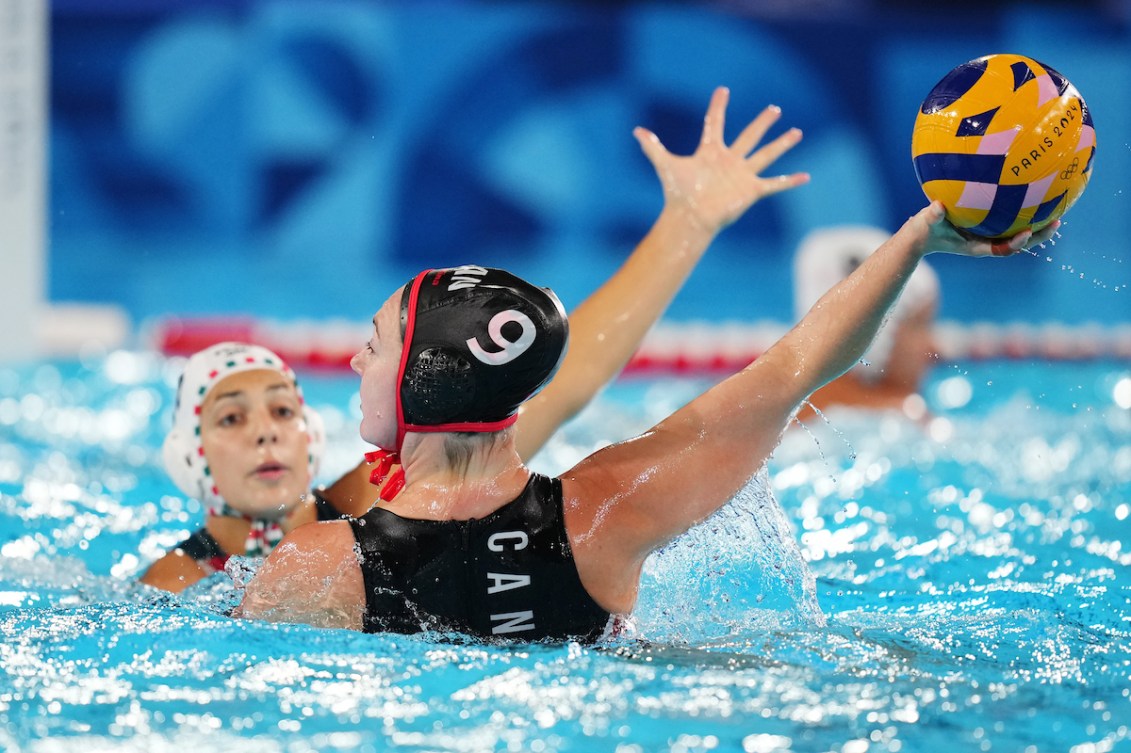 A water polo player prepares to throw the ball while in the pool