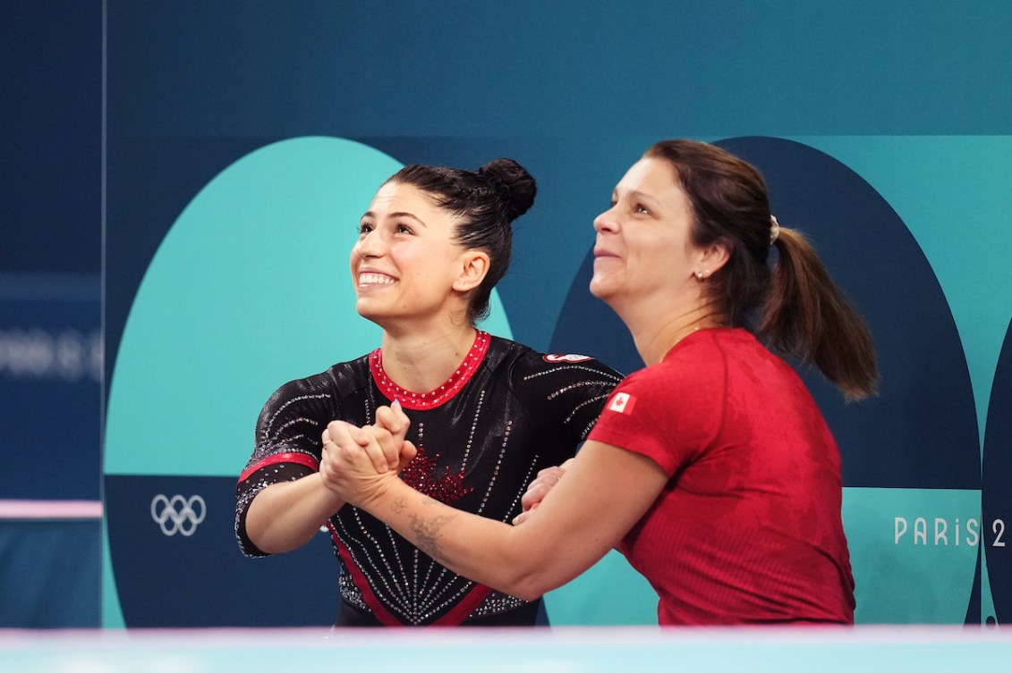 Sophiane Methot and her coach hold hands as they look to the scoreboard with big smiles 