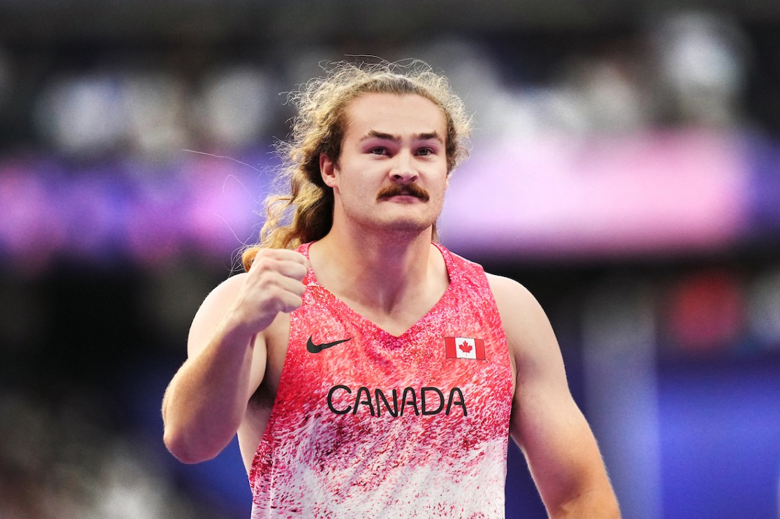 Ethan Katzberg pumps his fist while wearing a pink singlet