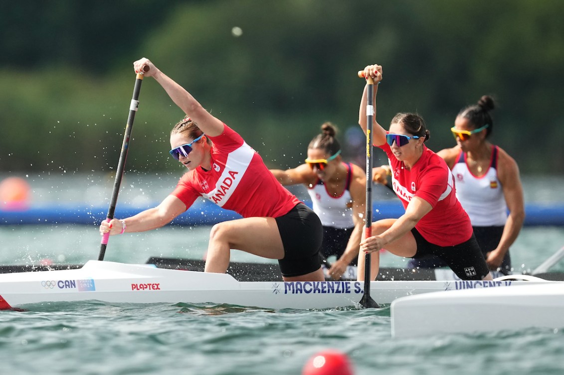 Sloan Mackenzie and Katie Vincent paddle their canoe while wearing red shirts