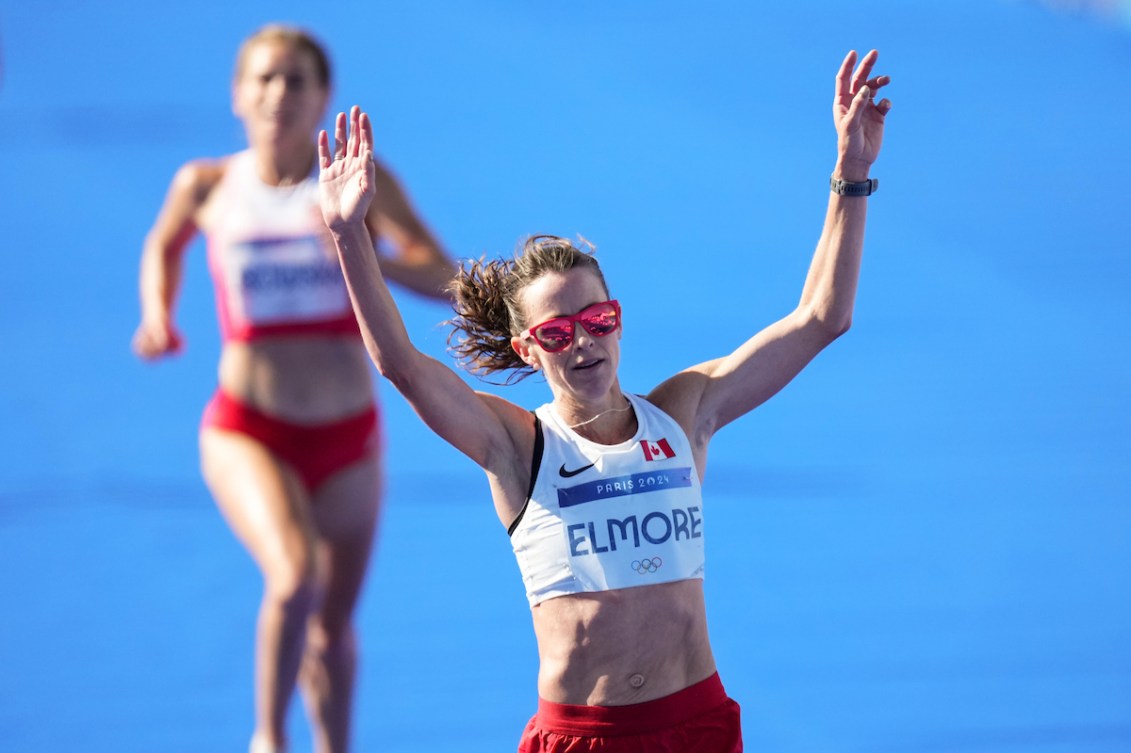 Malindi Elmore raises her arms as she crosses the finish line