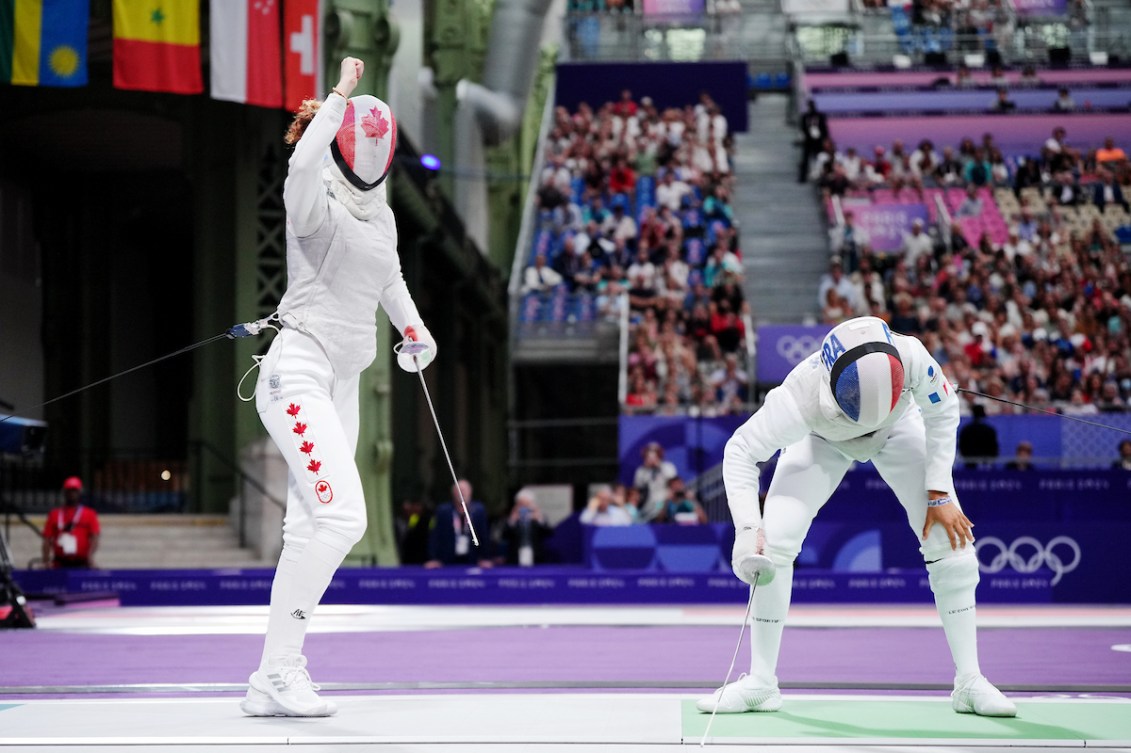 Eleanor Harvey pumps her fist in the air while her French fencing opponent leans on her knees in sadness