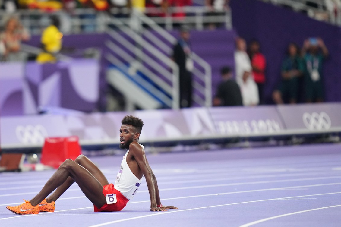 Mohammed Ahmed sits on the track in exhaustion after the 10,000m 