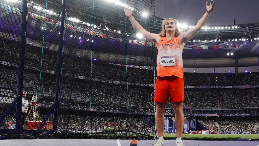 Ethan Katzberg raises his arms in the air while standing in the hammer throw circle