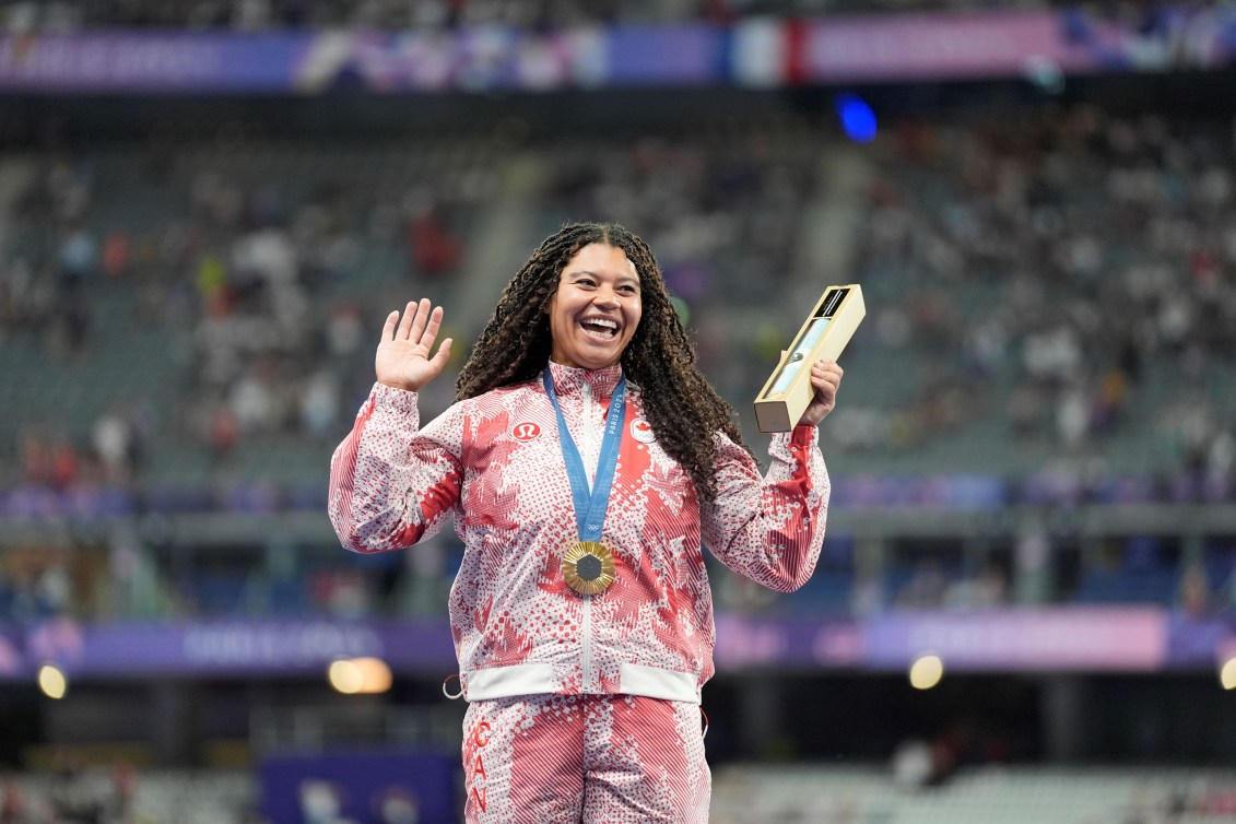 Camryn Rogers wears a gold medal with a red and white track suit