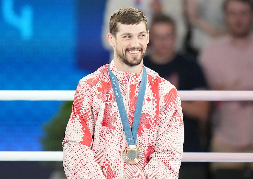 Wyatt Sanford wears a bronze medal with his red and white track suit 