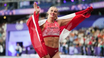 Alysha Newman waves with the Canadian flag draped over her shoulders