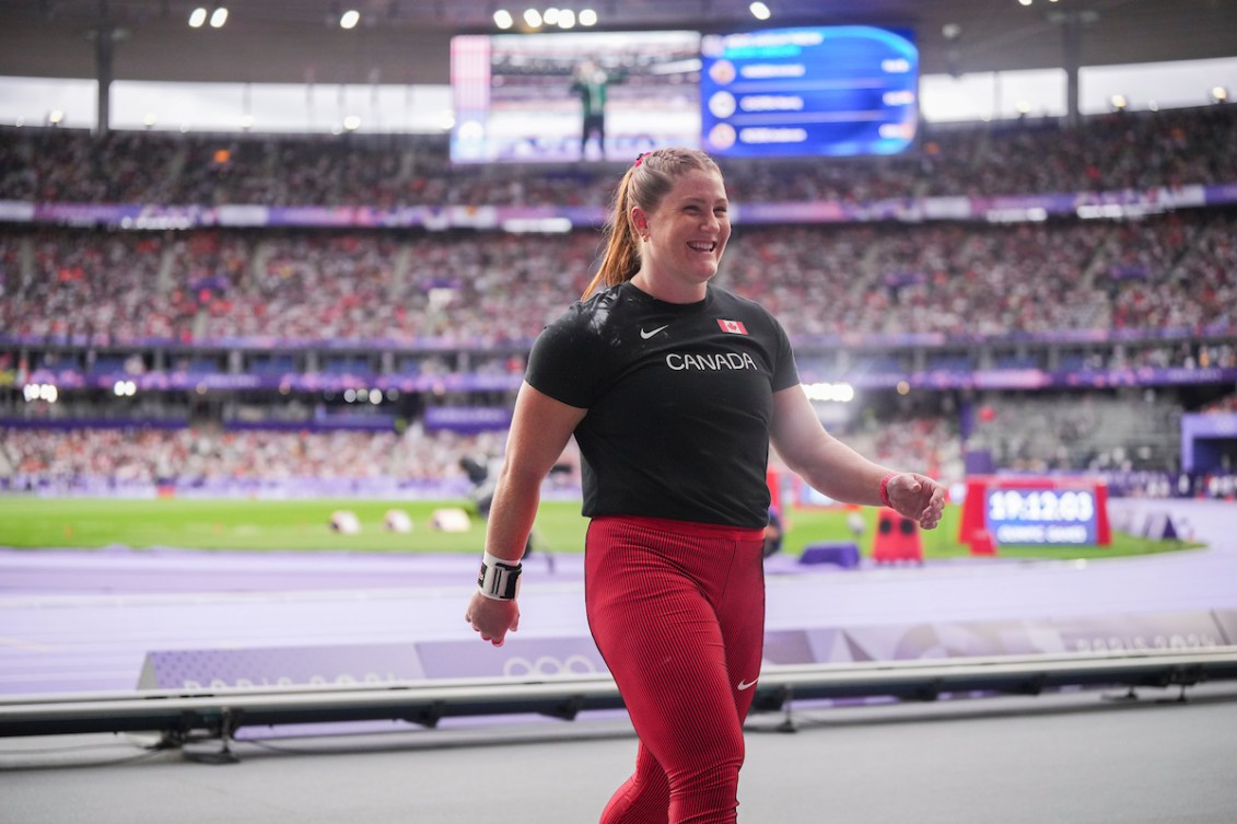 Sarah Mitton in black shirt and red pants walks on the track 