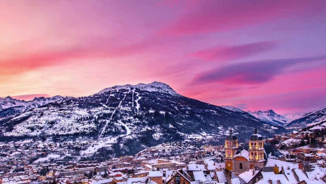 Sunset over a snow covered mountain with a town at its base