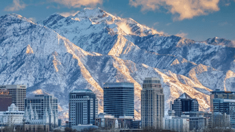 A snow covered mountain stands behind the cityscape of Salt Lake City