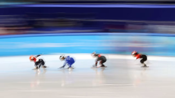 four speed skaters are blurred in motion