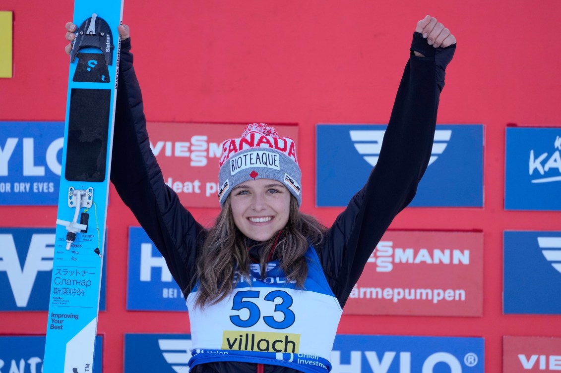 Abigail Strate holds her hands over her head in celebration after her third place at the Women's Normal Hill Individual Ski Jumping World Cup event in Villach, Austria