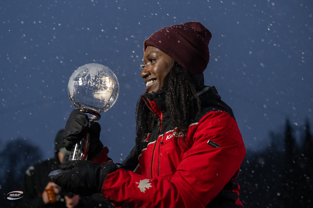 Cynthia Appiah in a red jacket holds a Crystal Globe trophy in her hands 