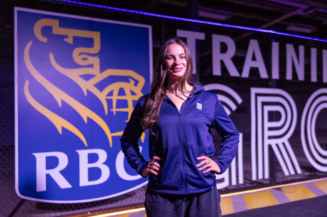 Penny Oleksiak stands in front of an RBC logo with her hands on her hips