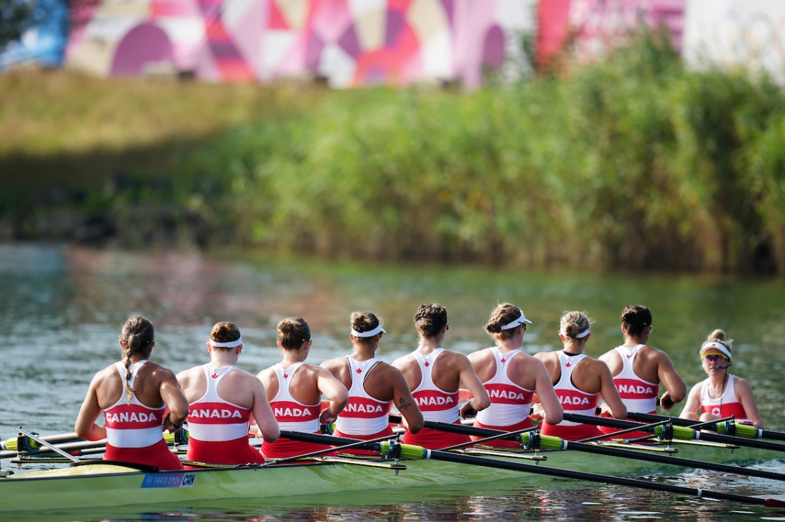 The Canadian women's rowing eight team is pictured from behind. Each of their singlets say Canada on the back