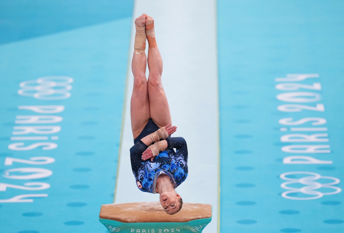 Ellie Black is upside down while performing a vault