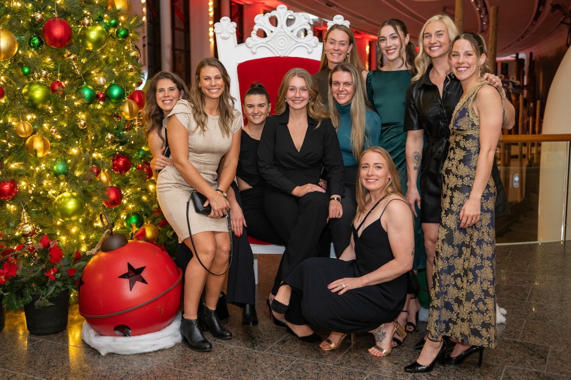 A group of female athletes pose next to a Christmas tree