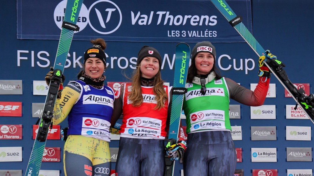 Three female ski cross athletes stand on a podium