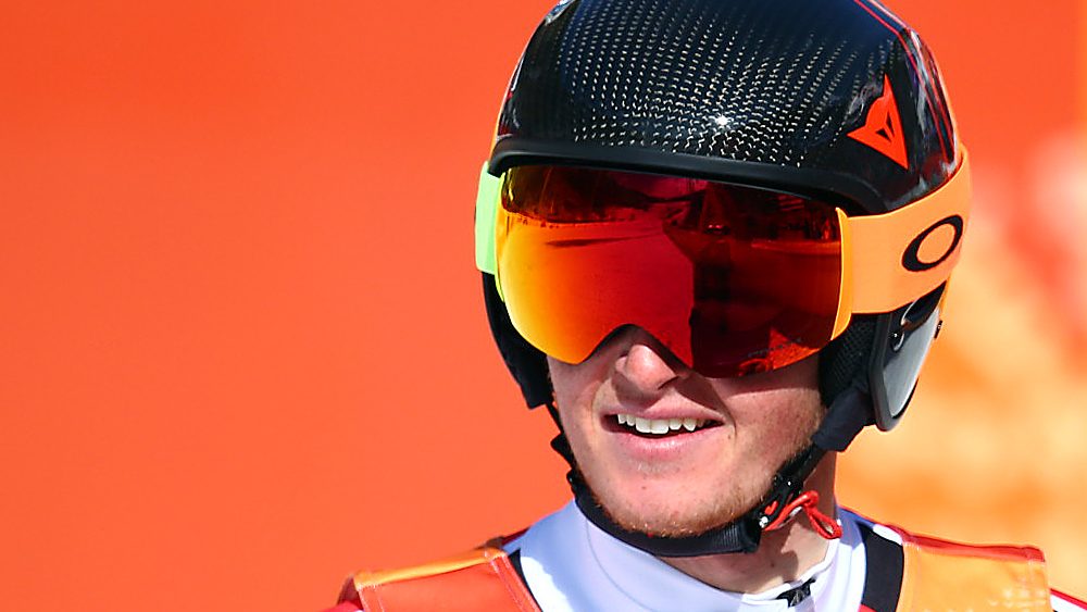 Broderick Thompson wears a helmet and goggles against an orange background