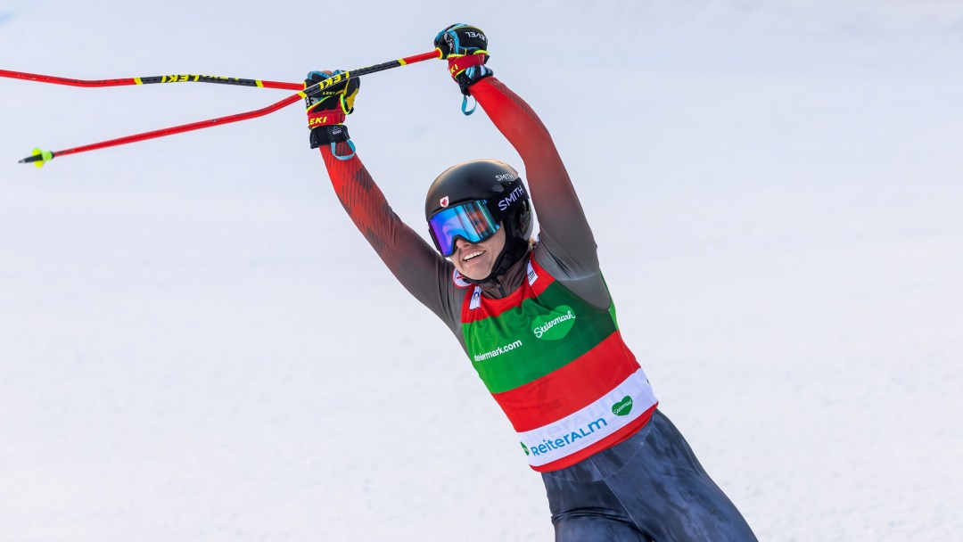 India Sherret holds he ski poles up over her head in celebration