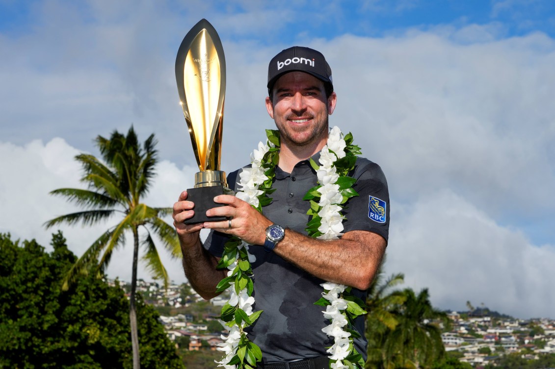 Nick Taylor poses with his trophy while wearing a lei