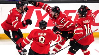 Team Canada hockey players hug and yell in celebration