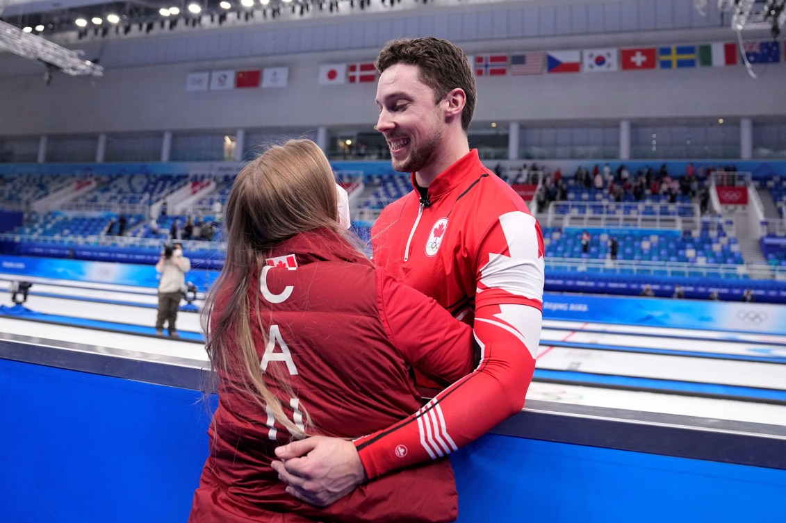 Brett Gallant reaches over blue boards to hug Jocelyn Peterman