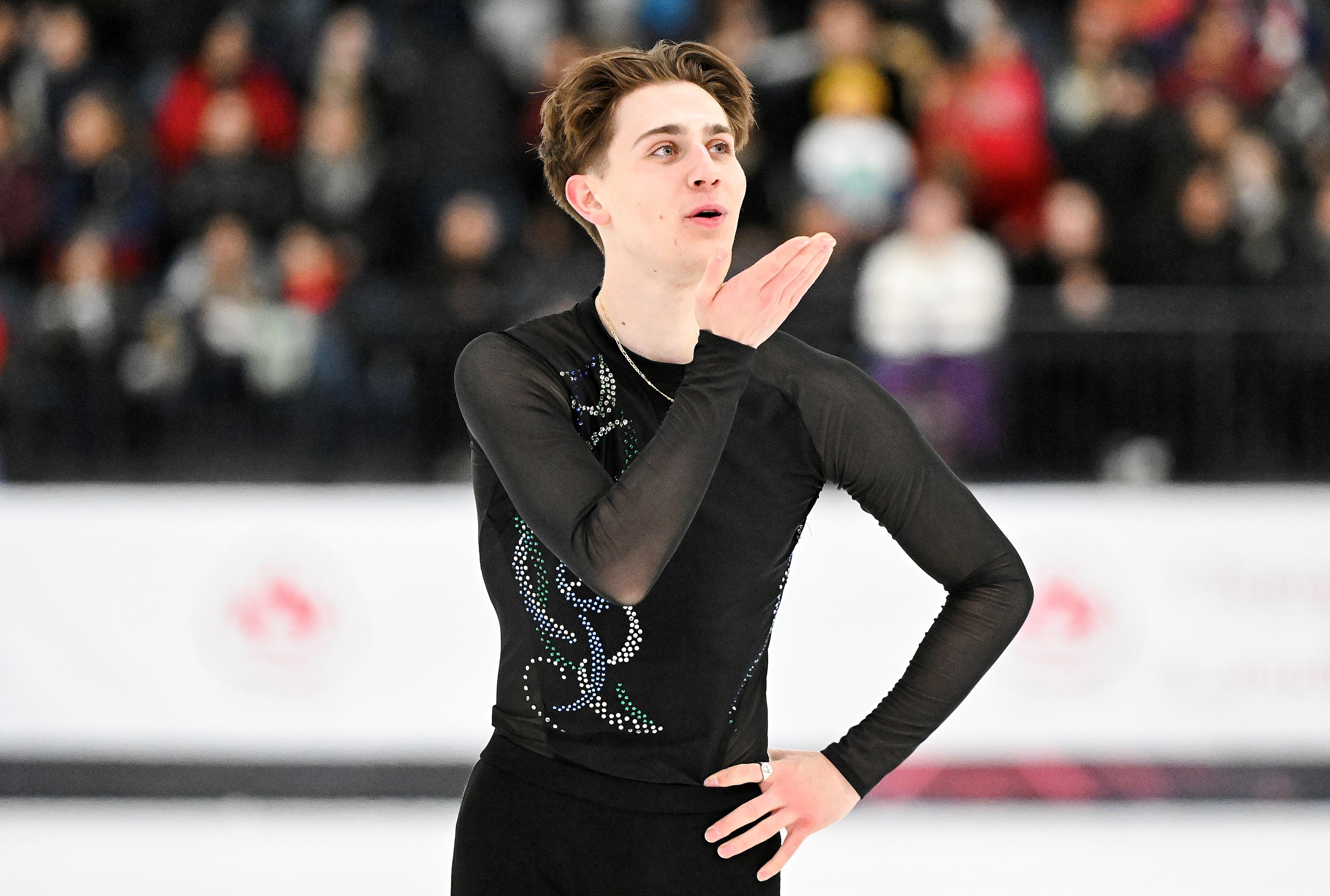 Roman Sadovsky dressed in a black costume blows a kiss