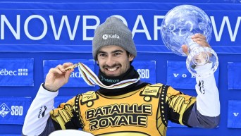 Eliot Grondin, of Sainte-Marie, Que., raises the Crystal Globe for the season’s overall winner, Sunday, April 6, 2025 at the FIS snowboard cross world cup event at Mont-Sainte-Anne resort in Beaupre, Quebec.