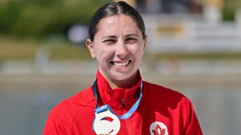 Katie Vincent smiles with gold medal on podium, after winning C1 500m final in Poland.