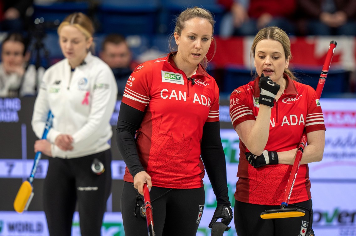 Dressed in red jackets, Rachel Homan and Tracy Fleury discuss a shot