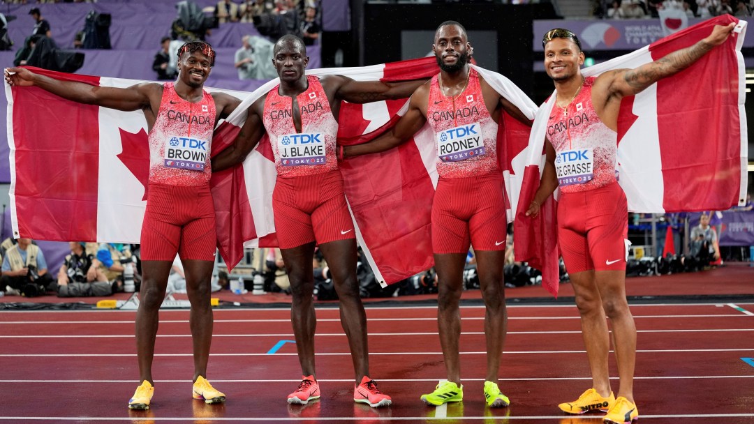 Canada's 4x100m relay team poses with Canadian flags held behind them