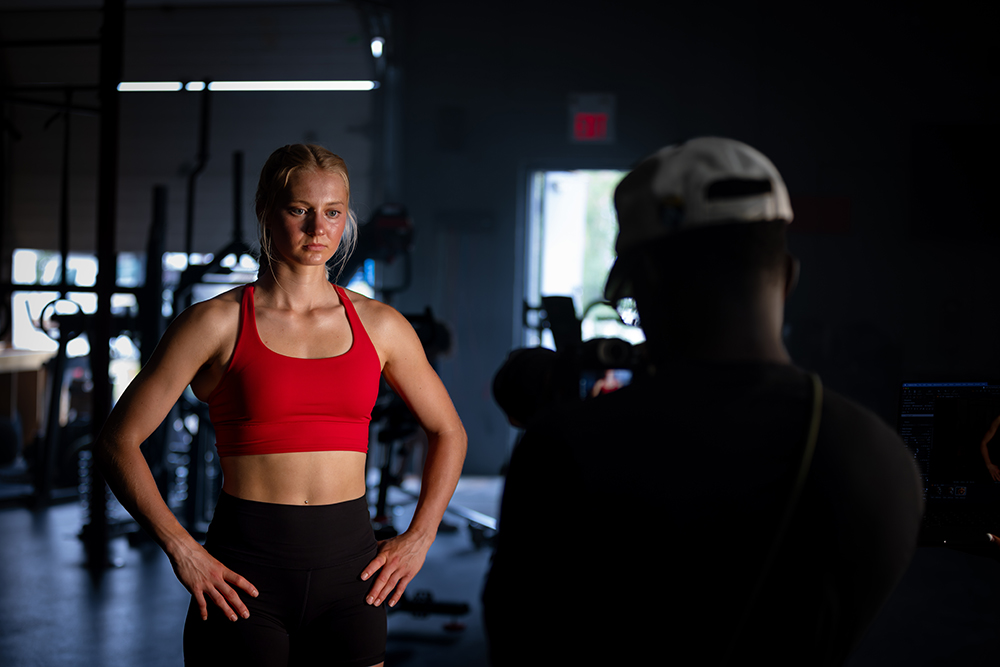 Sonjia Schmidt wearing red standing with hands on the hips in front of a camera. 