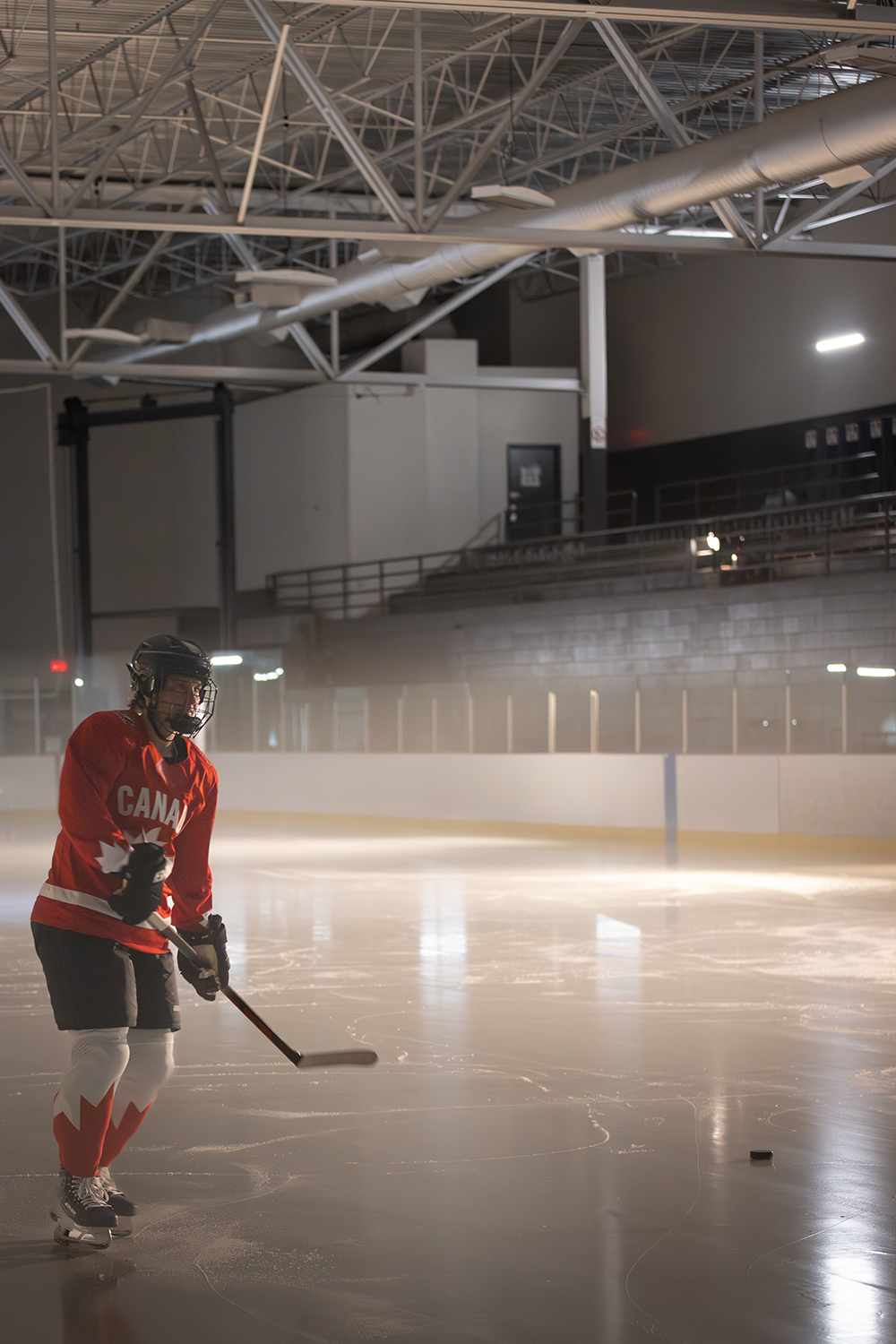 Marie-Philip Poulin in an indoor arena wearing Team Canada hockey gear and red jersey. 