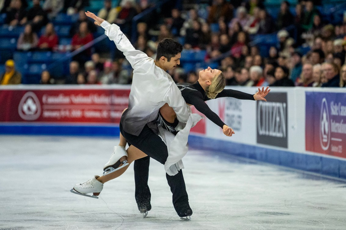 Marjorie Lajoie in a black dress is lifted by Zachary Lagha in black pants and white top