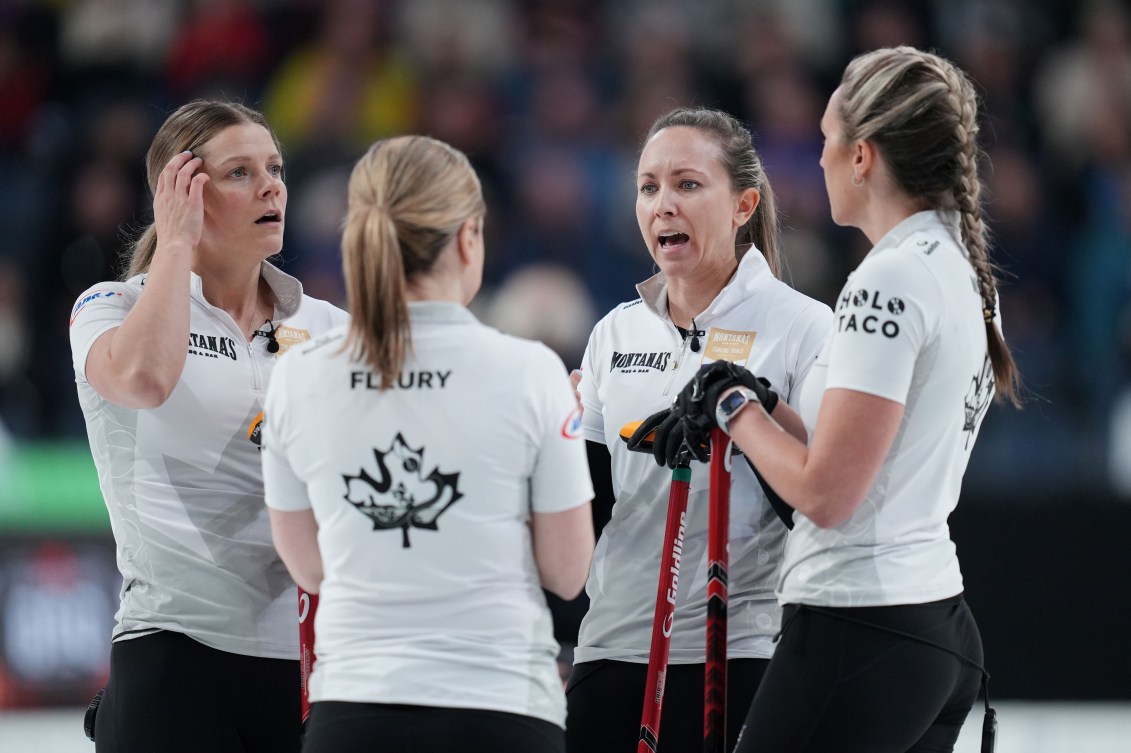 Four women curlers in white shirts have a discussion
