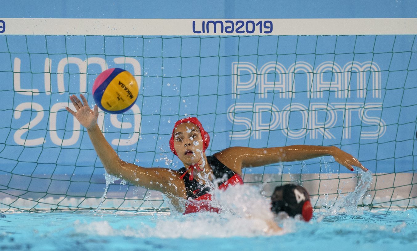 Une gardienne de but arrête un ballon au waterpolo.