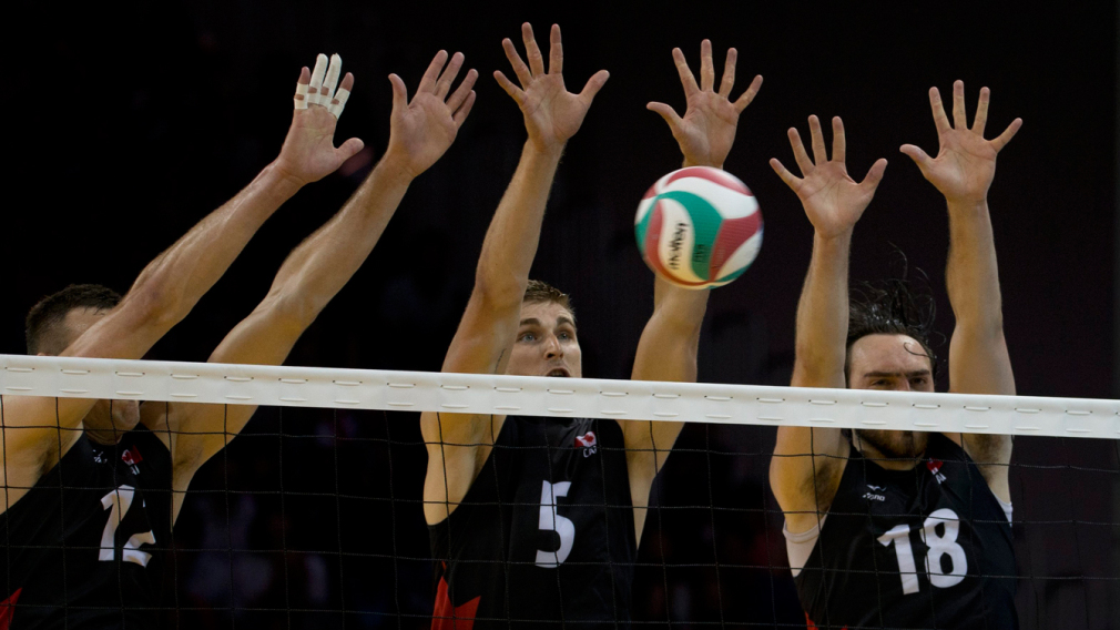 Trois joueurs canadiens tentent de bloquer un smash au volleyball