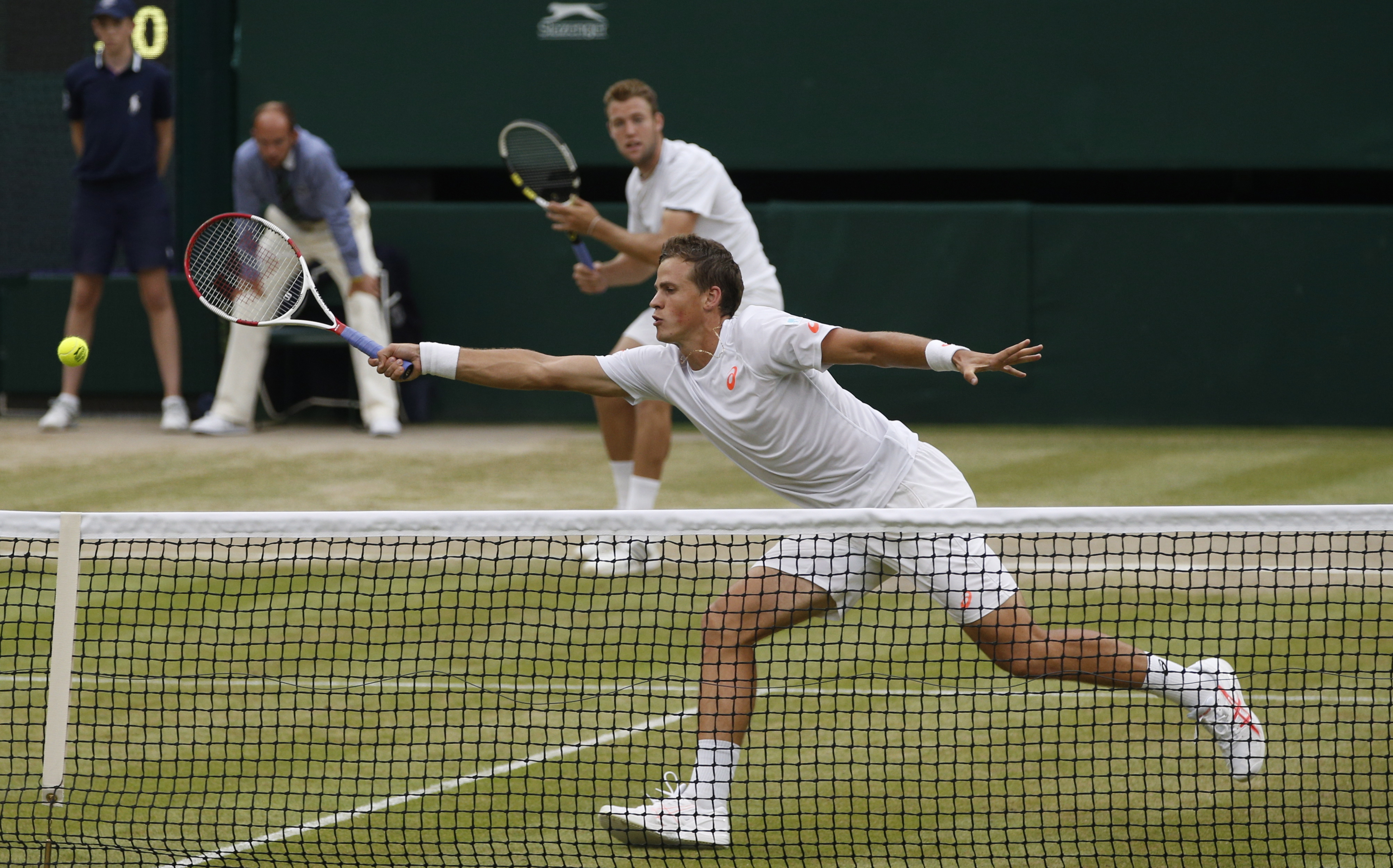 Vasek Pospisil of Canada, front, and Jack Sock of the U.S play a return during the men's doubles final against Bob Bryan and Mike Bryan of the U.S at the All England Lawn Tennis Championships in Wimbledon, London, Saturday, July 5, 2014. (AP Photo/Pavel Golovkin)