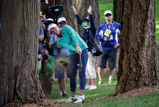 Brooke Henderson frappe sa balle entre deux arbres au 18e trou du Championnat de LPGA au Country Club de Sahalee samedi, le 11 juin 2016 (AP Photo/ Elaine Thompson)