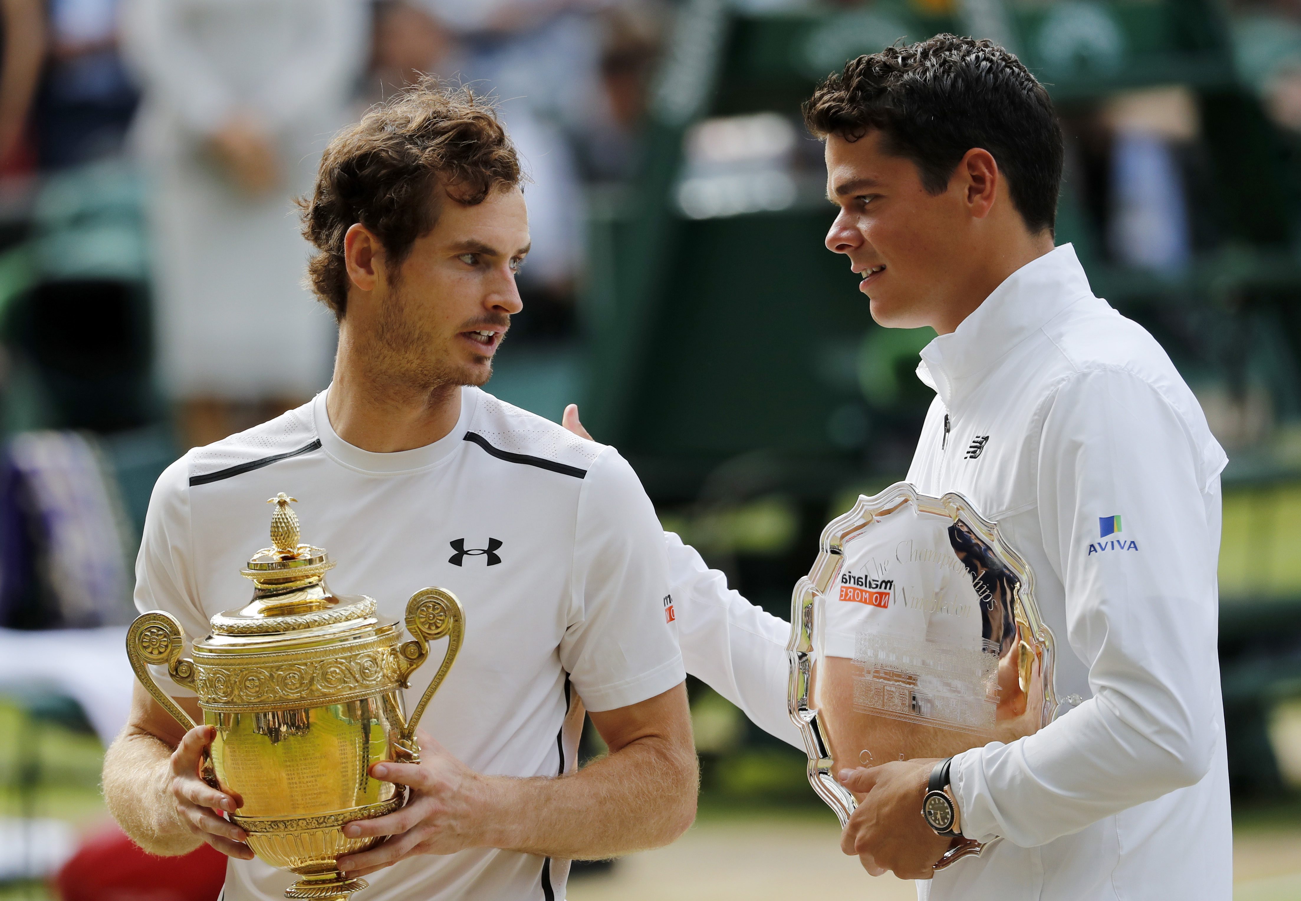 Andy Murray of Britain, left, holds up his trophy after beating Milos Raonic of Canada, right, in the men's singles final on day fourteen of the Wimbledon Tennis Championships in London, Sunday, July 10, 2016. (AP Photo/Ben Curtis)