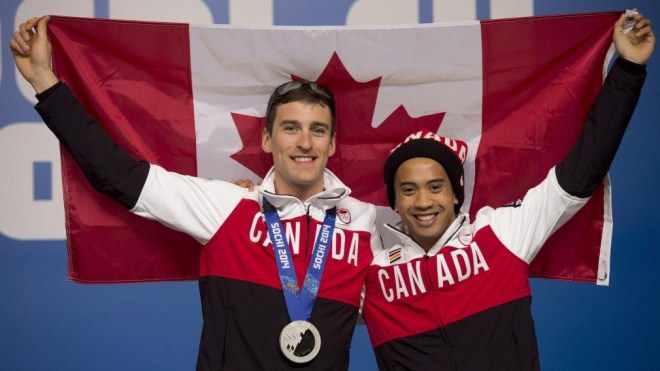 Gilmore Junio posant avec Denny Morrison, tenant le drapeau canadien
