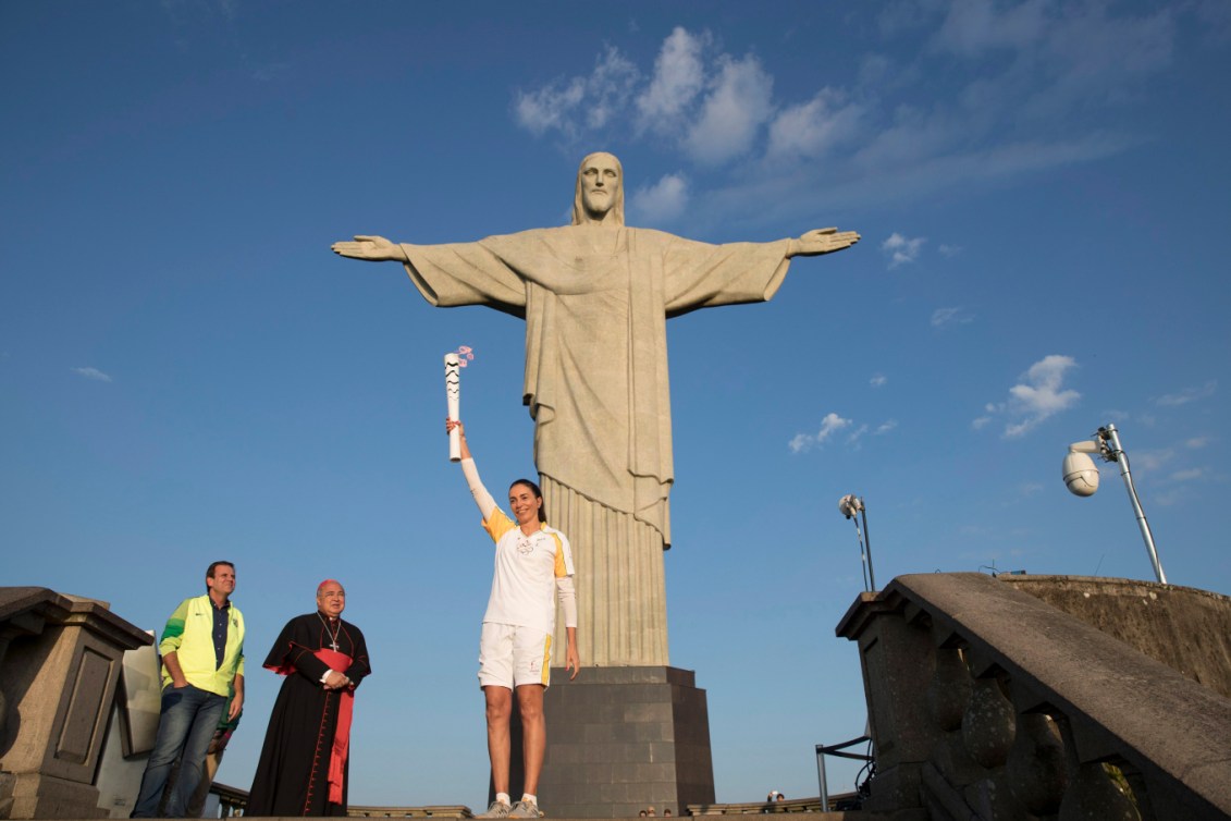 Une athlète brésilienne pose avec la flamme olympique devant le Chris Rédempteur.