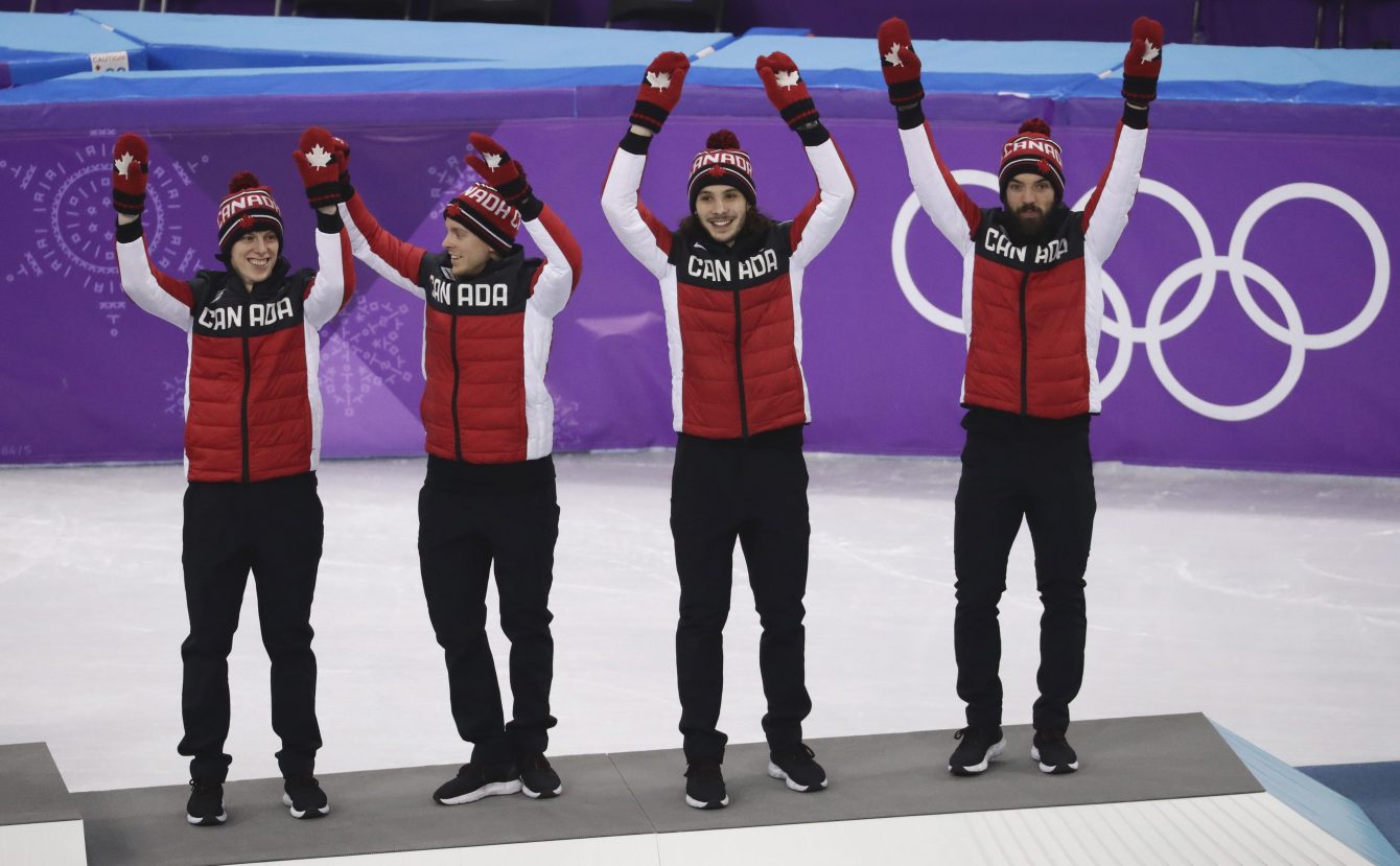 Charle Cournoyer, Pascal Dion, Samuel Girard et Charles Hamelin d'Équipe Canada célèbrent sur le podium après avoir remporté la médaille de bronze au relais 5000 m en courte piste aux Jeux olympiques de PyeongChang, en Corée du Sud, le 22 février 2018.
