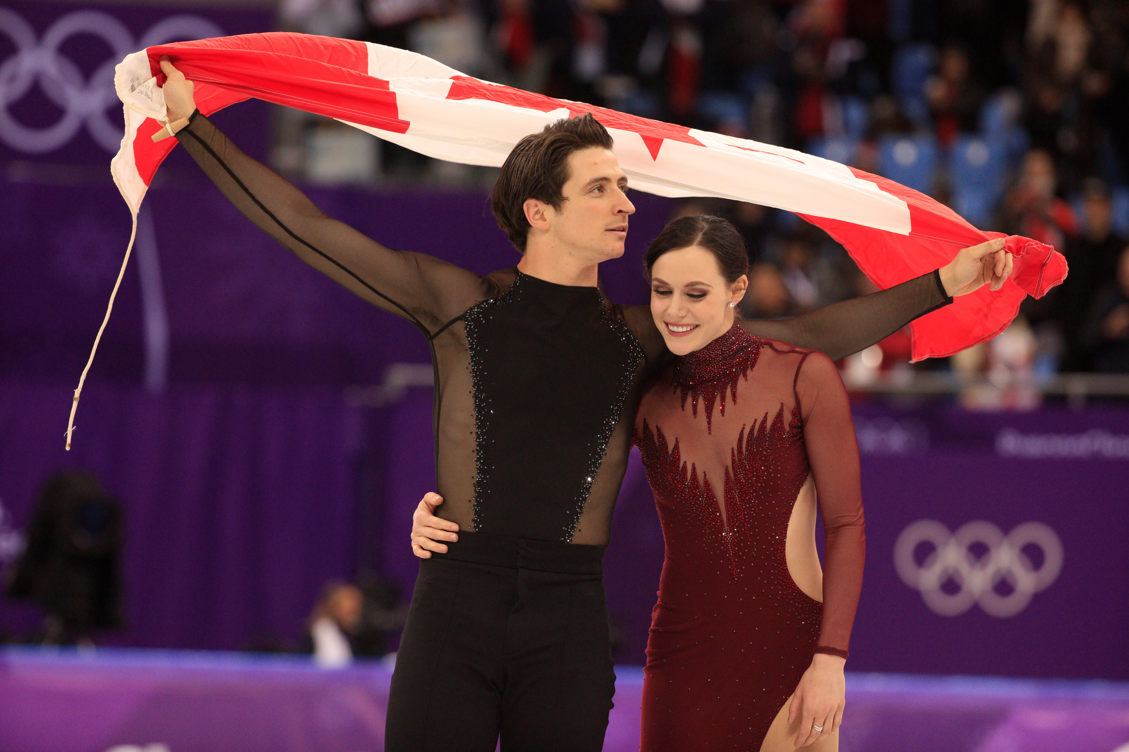 Tessa Virtue et Scott Moir effectuent un tour de piste avec le drapeau canadien après avoir décroché la médaille d'or en danse sur glace aux Jeux olympiques de PyeongChang, en Corée du Sud, le 20 février 2018.