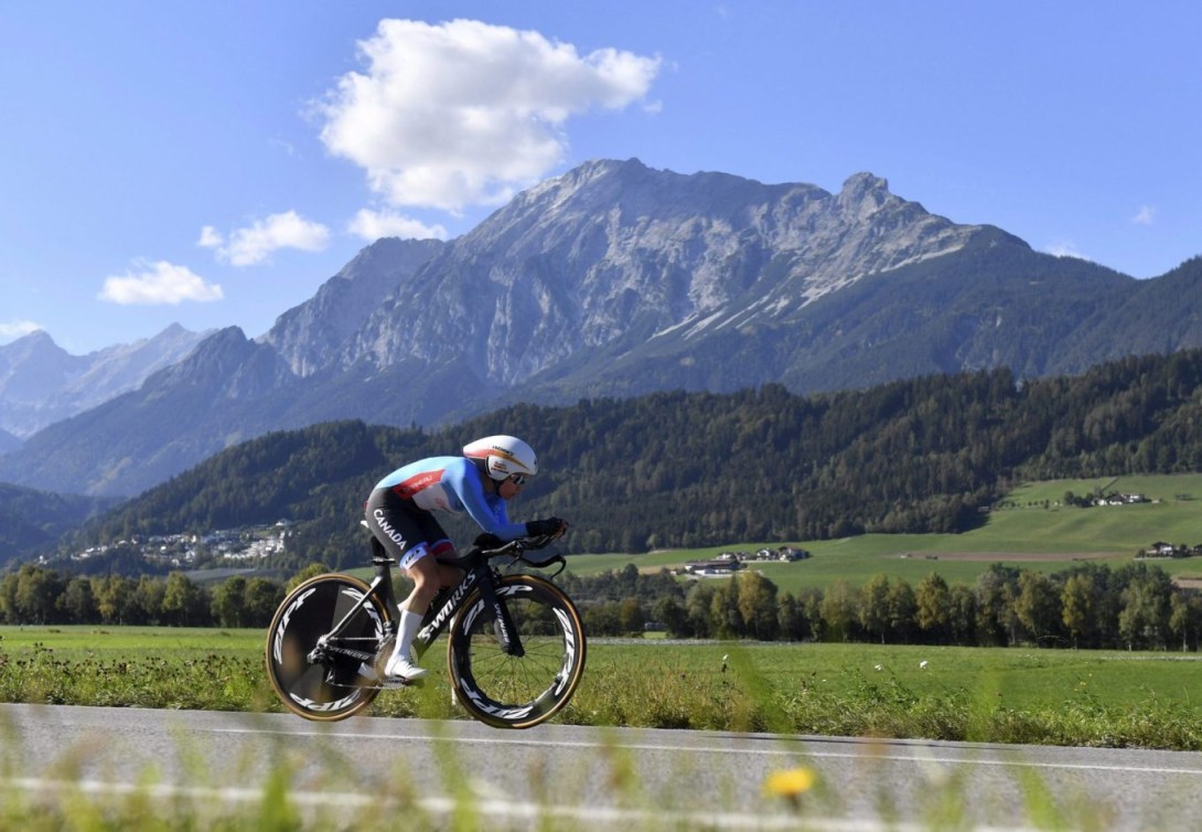 Une cycliste canadienne sur route, avec un magnifique paysage montagneux en arrière-plan.