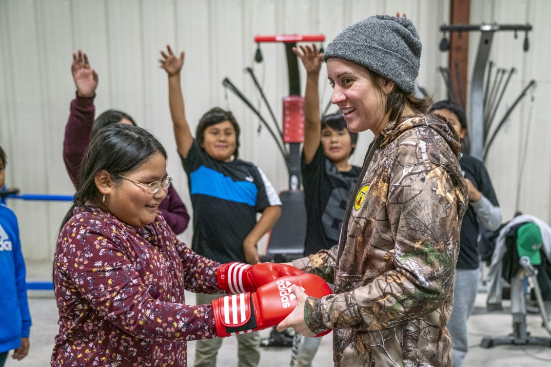 Mary Spencer aide une élève à mettre des gants de boxe.